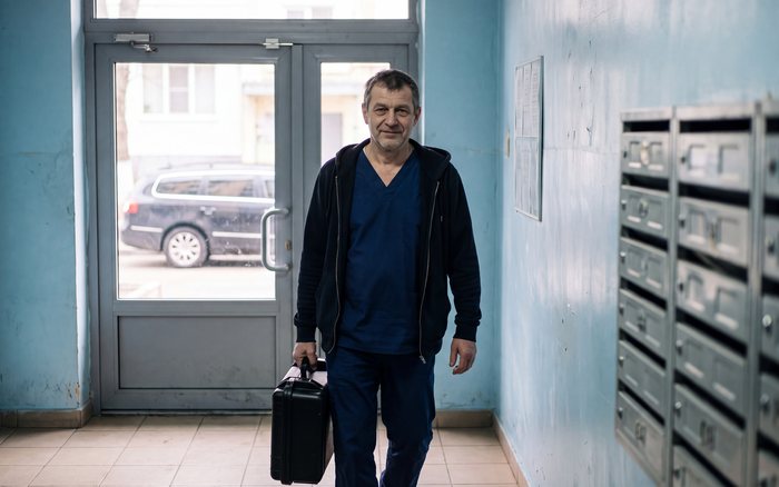 Лікар із медичною валізою заходить у під'їзд